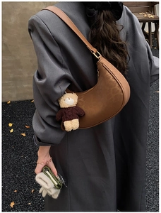 Detail of vintage brown crescent hobo bag with a cute bear charm on a wool coat
