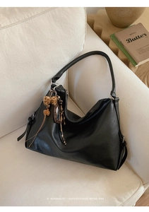 Détail du sac cabas en cuir noir avec nœud léopard sur un canapé minimaliste