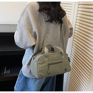 Detail view of light green nylon crossbody bag with adjustable strap and side brand tag