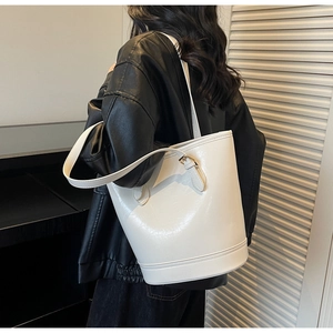 Detail view of the glossy white bucket tote bag shown on model for size and style reference