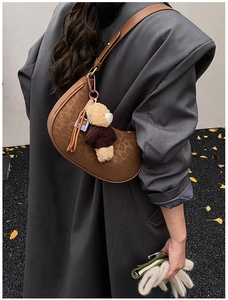 Detailed view of brown leopard print half-moon underarm bag with cute teddy bear charm
