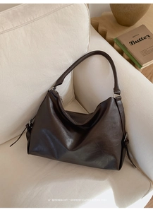 Détail du sac cabas en cuir souple marron foncé sur canapé beige au style rétro