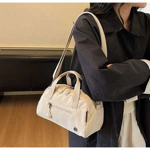 Detail of minimalist cream crossbody bag showing durable nylon texture and adjustable strap