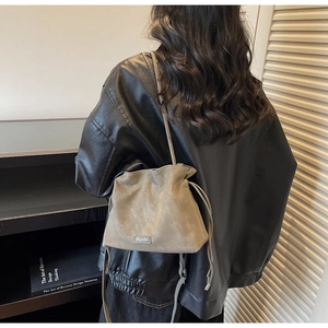 Detailed view of taupe drawstring bucket bag with thin shoulder strap on model