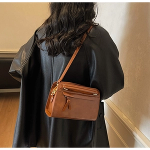 Détails du sac bandoulière marron avec fermeture éclair nouée et accents dorés