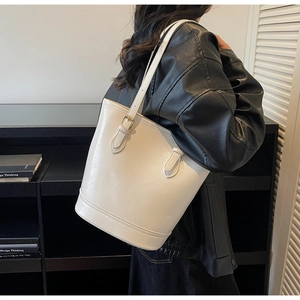 Detail of white glossy leather tote bag with thin straps and golden metal buckles