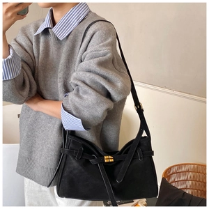 Detail of black suede shoulder bag featuring a gold square twist lock and cross strap