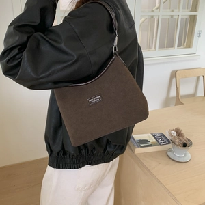 Retro brown suede underarm bag detail with leather logo label and metallic hardware