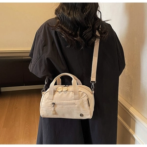 Rear view of model wearing a large beige nylon crossbody bag with adjustable strap