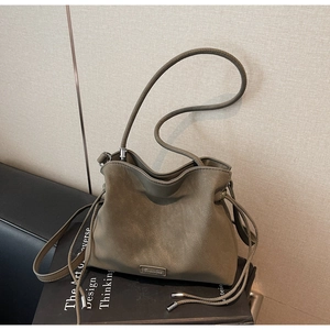 Detail of olive green drawstring bucket bag with silver logo on soft matte leather texture