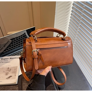 Détail d'un sac à main marron en similicuir vintage avec poignée et finitions à glands