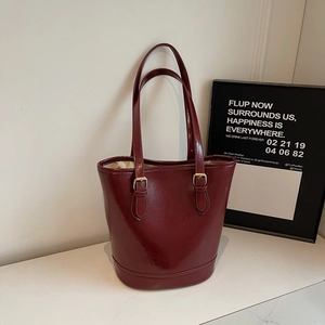 Detail view of burgundy leather tote bag with glossy texture and gold buckles