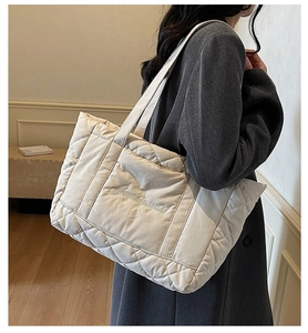 Quilted puffer tote bag in cream white with cursive embroidery shown on model