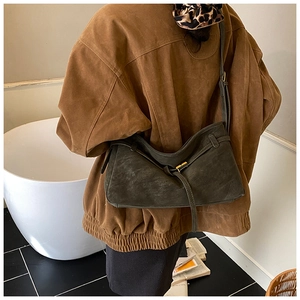 Detail view of a vintage dark green suede shoulder bag with elegant gold metal buckles