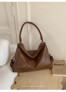 Détail du grand sac cabas en cuir marron foncé sur un support en bois minimaliste