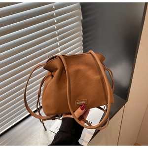 Close-up of brown leather bucket bag with drawstring detail and elegant brand logo
