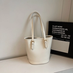 Detail of white tote bag showing golden metal adjustment buckles and leather strap