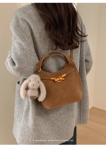 Dettaglio borsa retrò in pelle marrone con chiusura dorata e ciondolo a forma di coniglio