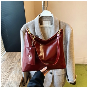 Detailed view of glossy burgundy PU leather tote bag with a matching mini pouch charm