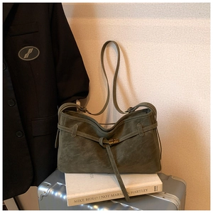 Close-up of deep olive green suede bag with decorative leather strap and metal buckle