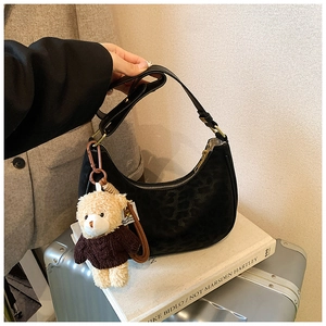 Detail of black leopard pattern suede hobo bag with a cute bear plush keychain charm