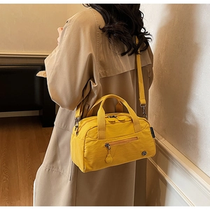 Detail of a bright yellow nylon crossbody bag shown with a model for casual styling