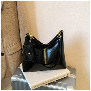 Close-up of glossy black hobo bag with gold hardware and a small coin purse charm