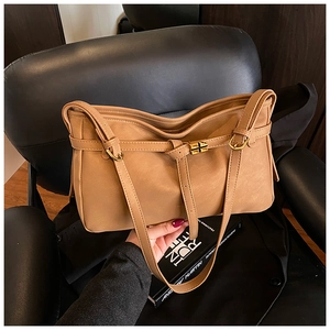 Detailed view of camel faux leather tote with golden metal clasp and cross strap decor