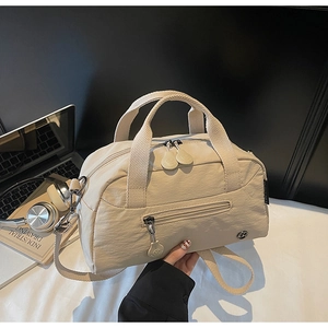 Detail view of beige nylon crossbody bag with dual handles and wide adjustable strap