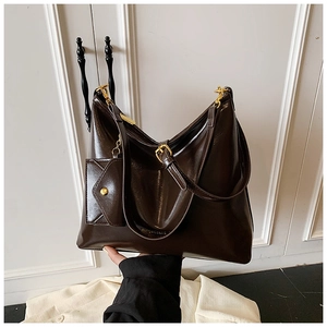Detail of deep brown glossy leather tote bag with gold hardware and small hanging pouch