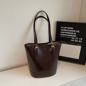 Detail of deep brown glossy oiled leather tote bag with adjustable thin shoulder strap