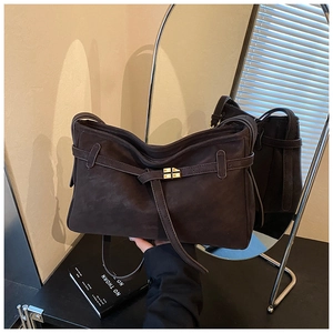 Detail of dark brown matte suede shoulder bag featuring a square gold metal buckle clasp