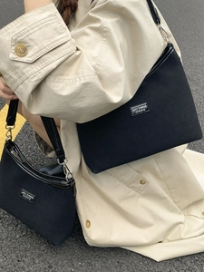Minimalist black canvas tote and crossbody bags shown in a stylish outdoor street setting