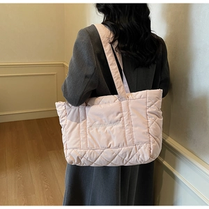 Lifestyle view of a light pink quilted tote bag with diamond stitching and embroidery