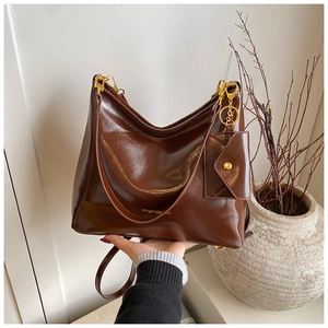 Detail of dark brown polished leather tote with gold hardware and mini coin purse