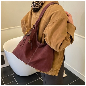 Détail du sac hobo bordeaux avec surpiqûres blanches et pendentifs décoratifs en bois