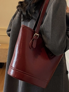 Minimalist burgundy leather tote bag with adjustable strap and vintage gold hardware