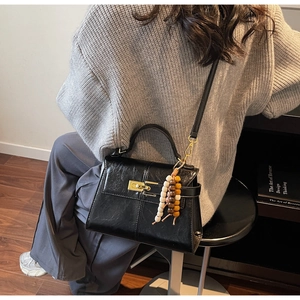 Detail of black glossy oil wax leather handbag with golden lock and colorful bead tassel