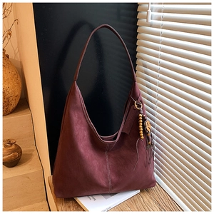 Détail du sac hobo en daim bordeaux avec surpiqûres blanches et breloque florale