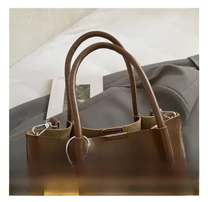 Detail view of brown leather bucket bag with cylindrical handles and yellow floral charm