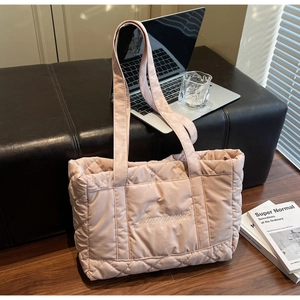 Detail of light pink quilted tote bag with diamond stitching and embroidered logo detail