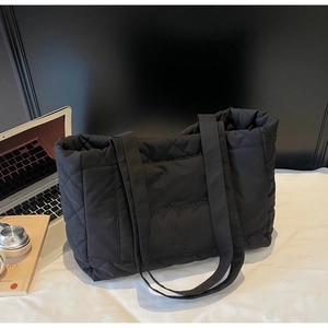 Detailed view of black quilted tote bag with diamond stitching and embroidery