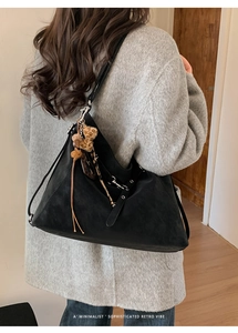 Vue portée du grand sac fourre-tout rétro noir avec breloque léopard et franges