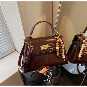 Close-up of a vintage dark brown handbag with gold hardware and ethnic beaded charm decoration