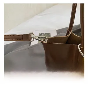 Detail of silver metal swivel hook and textured brown leather strap on luxury shoulder bag