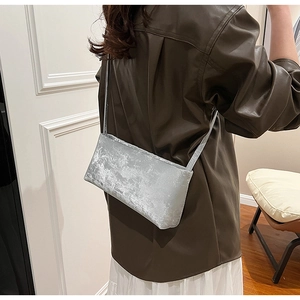 Detail view of a silver rectangular underarm bag with a vintage velvet texture effect
