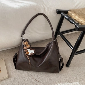 Détail du sac cabas marron café vintage avec texture cuir et accessoire de charme en forme de cœur