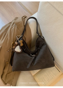 Détail d'un sac cabas rétro marron foncé sur canapé avec breloque cœur léopard