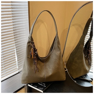 Détail du sac hobo vert olive avec pompon en perles de bois et similicuir texturé