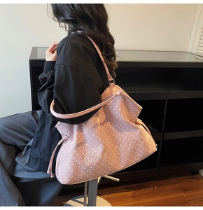 Pink tote bag detail with white star prints and embroidered logo on shoulder